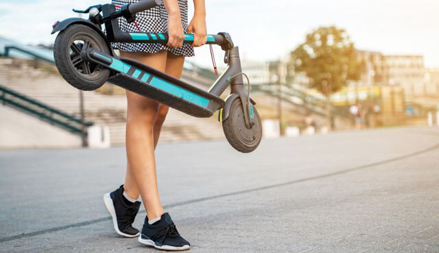 Junger Mann mit E-Scooter in der Hand