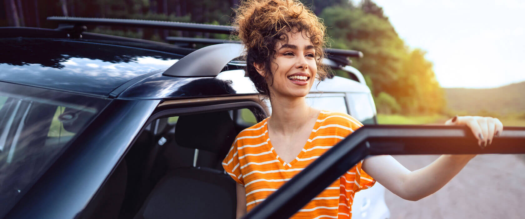 Auto und Mobilität -  Versicherungen für Privatkunden: junge Dame steht lässig vor dem blauen Auto