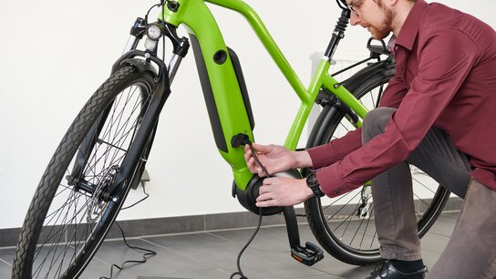 Überflutete Landschaft mit einer Sperrnis und einem Schild, das vor Hochwasser warnt. Wasser steht bis zur Brücke.