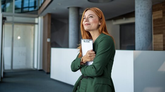 Zwei Männer im Geschäftsanzug sitzen in einem modern eingerichteten Büro und besprechen Dokumente. Sie lachen und sind freundlich.