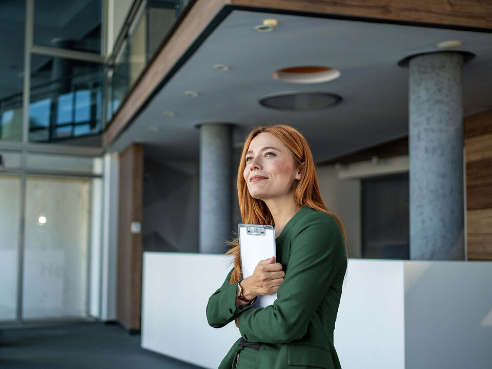 Zwei Männer im Geschäftsanzug sitzen in einem modern eingerichteten Büro und besprechen Dokumente. Sie lachen und sind freundlich.